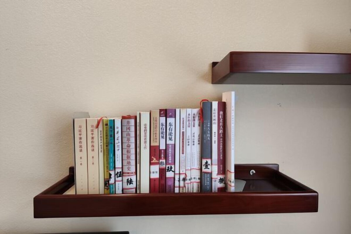 A wooden bookshelf with books against a plain wall.