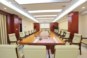Une salle de conférence équipée d’une longue table, de nombreuses chaises, d’un écran de projection et d’un pupitre pour les présentations.