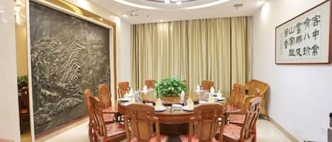A dining area with a round table, chairs, and a chandelier.
