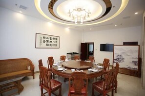 Une salle de conférence équipée d’une table ronde, de chaises, d’un canapé, d’un tableau et d’un téléviseur.