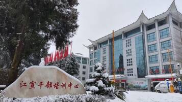 A building with a large sign in front, surrounded by snow-covered trees and a clear sky.