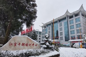 Un edificio con un letrero grande en primer plano, rodeado de árboles cubiertos de nieve y un cielo despejado.