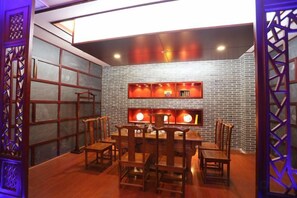 Un comedor con pared de ladrillo, sillas de madera y una mesa.
