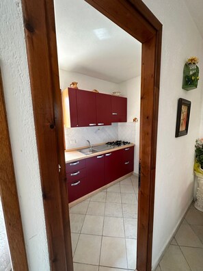 A kitchen with red cabinets, a sink, and a stove. - Beach Walk Apartments - San Teodoro (San Teodoro)