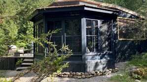 Una cabana de fusta amb un porxo cobert, envoltada d'arbres.