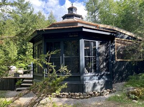 Eine Holzhütte mit überdachter Veranda, umgeben von Bäumen.