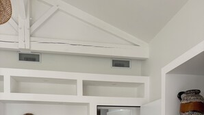 A hallway with white walls, a ceiling fan, a door leading to another room, and a white refrigerator. - SOLEO Vacation Home (Solférino)