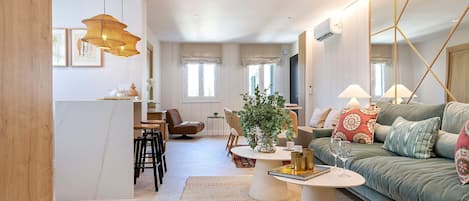 Un salon moderne comprenant un canapé, une table basse et un coin repas avec des chaises.