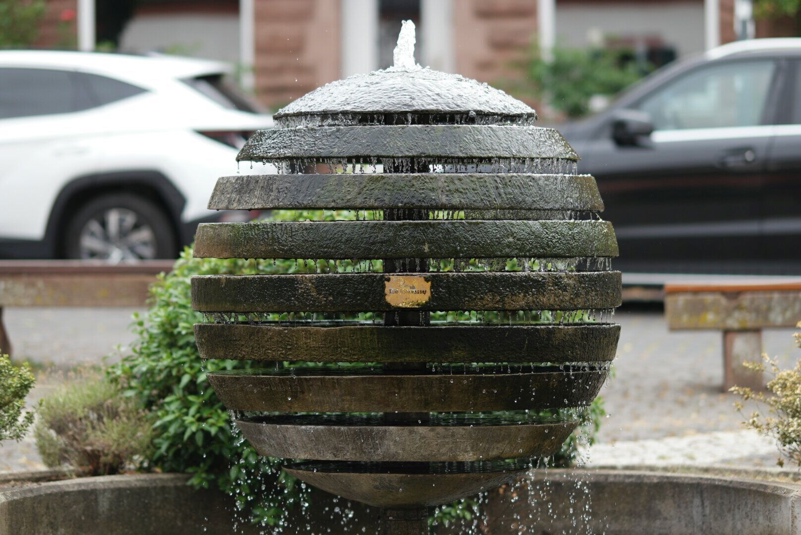 Un élément décoratif aquatique à plusieurs niveaux, entouré de verdure.
