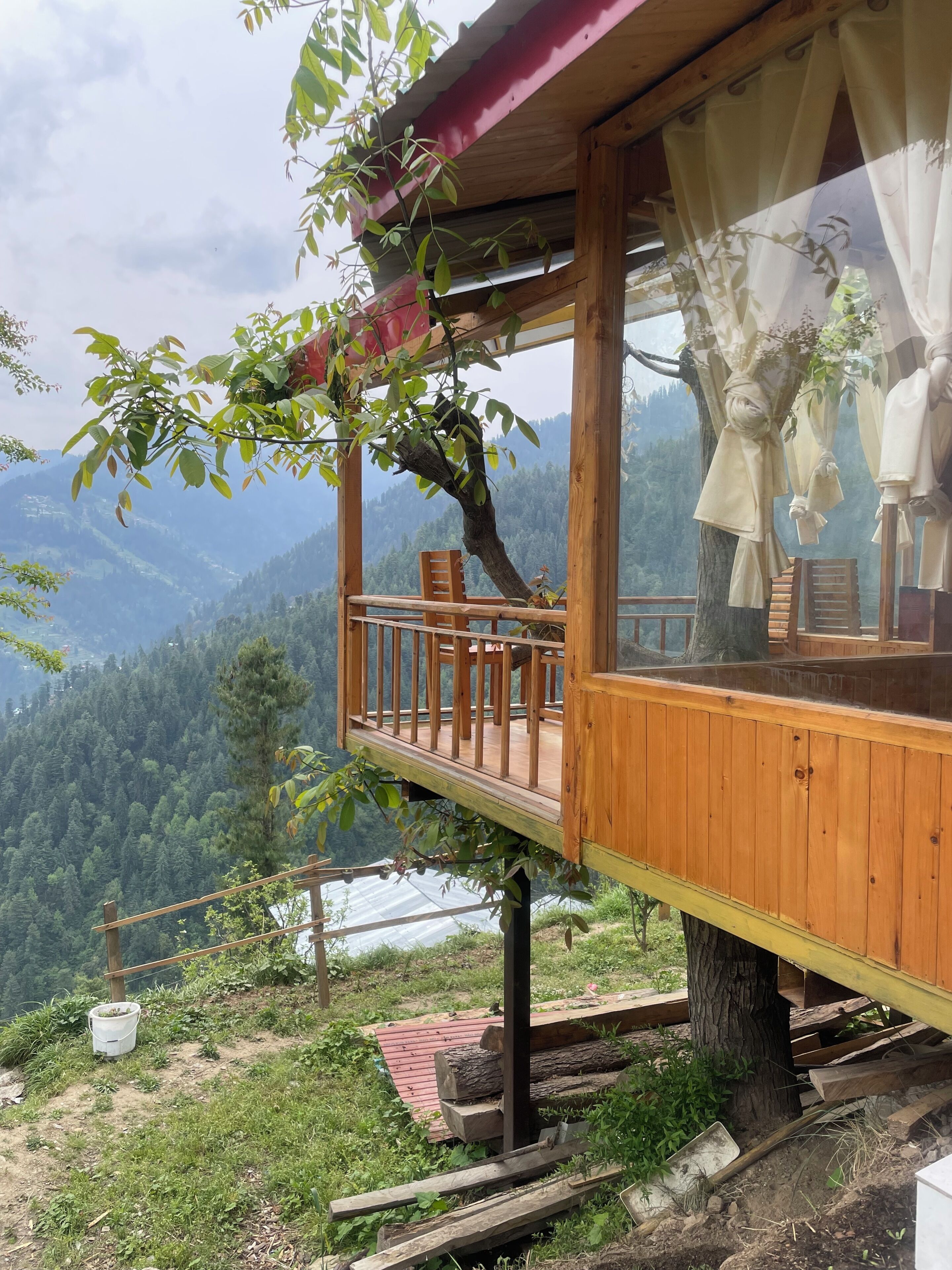 A wooden cabin with a balcony overlooking a mountainous landscape.