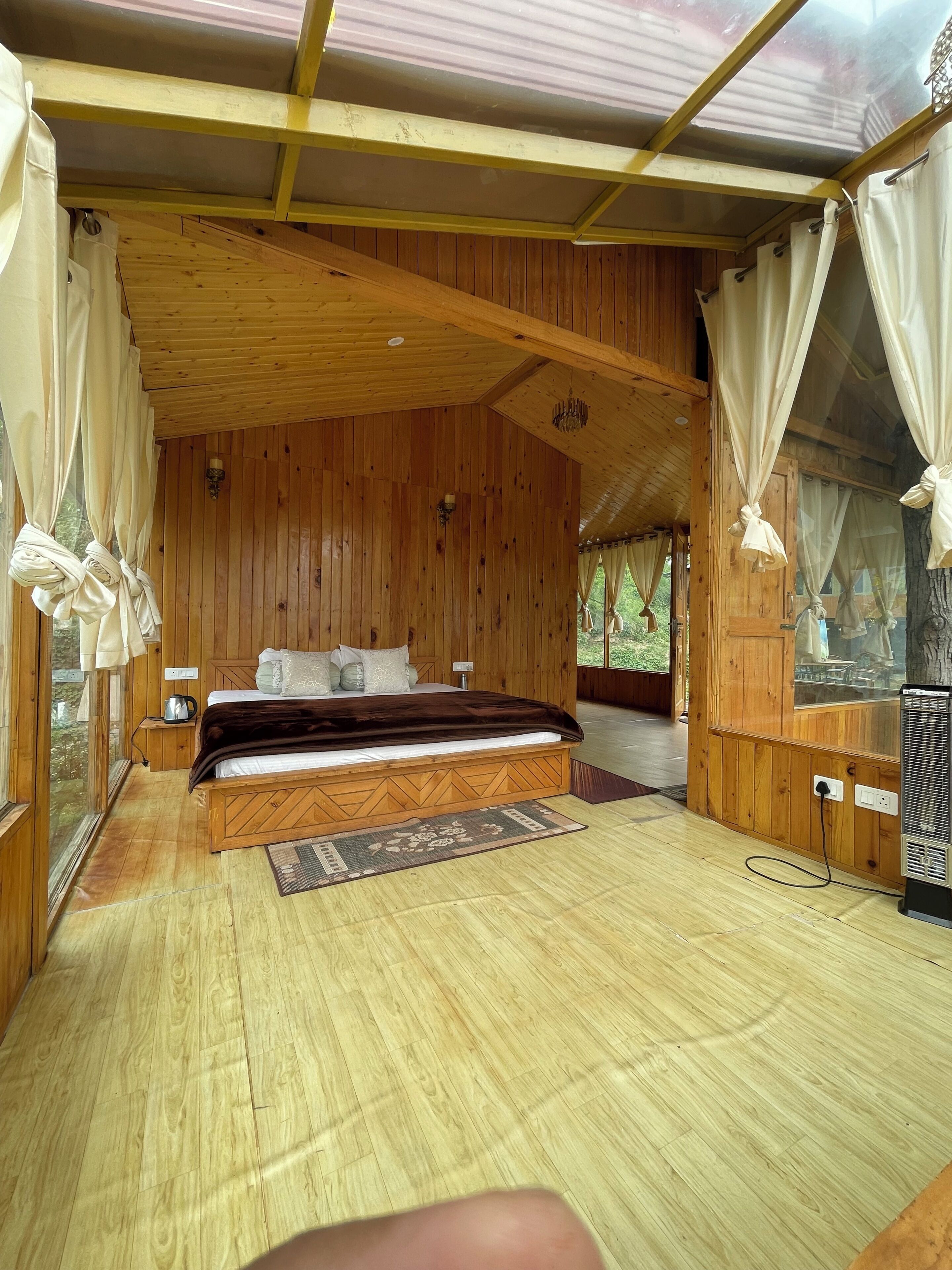 A wooden cabin bedroom with a bed, bedside table, and a heater.