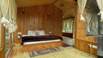 A wooden cabin bedroom with a bed, bedside table, and a heater.