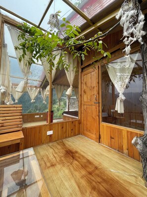 A wooden cabin with a glass ceiling, a bench, and a view of the outdoors. - Tranquil 1-bedroom cabin in marvelous Kullu for a cozy stay (kullu)