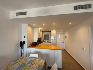 Eine kleine Küche mit einer Holz Arbeitsplatte, weißen Schränken und einem eingebauten Backofen.