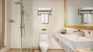A modern bathroom with a glass-enclosed shower, a toilet, a sink, and a large mirror. - Vienna International Hotel (Leshan Shizhong District Store) (Leshan)