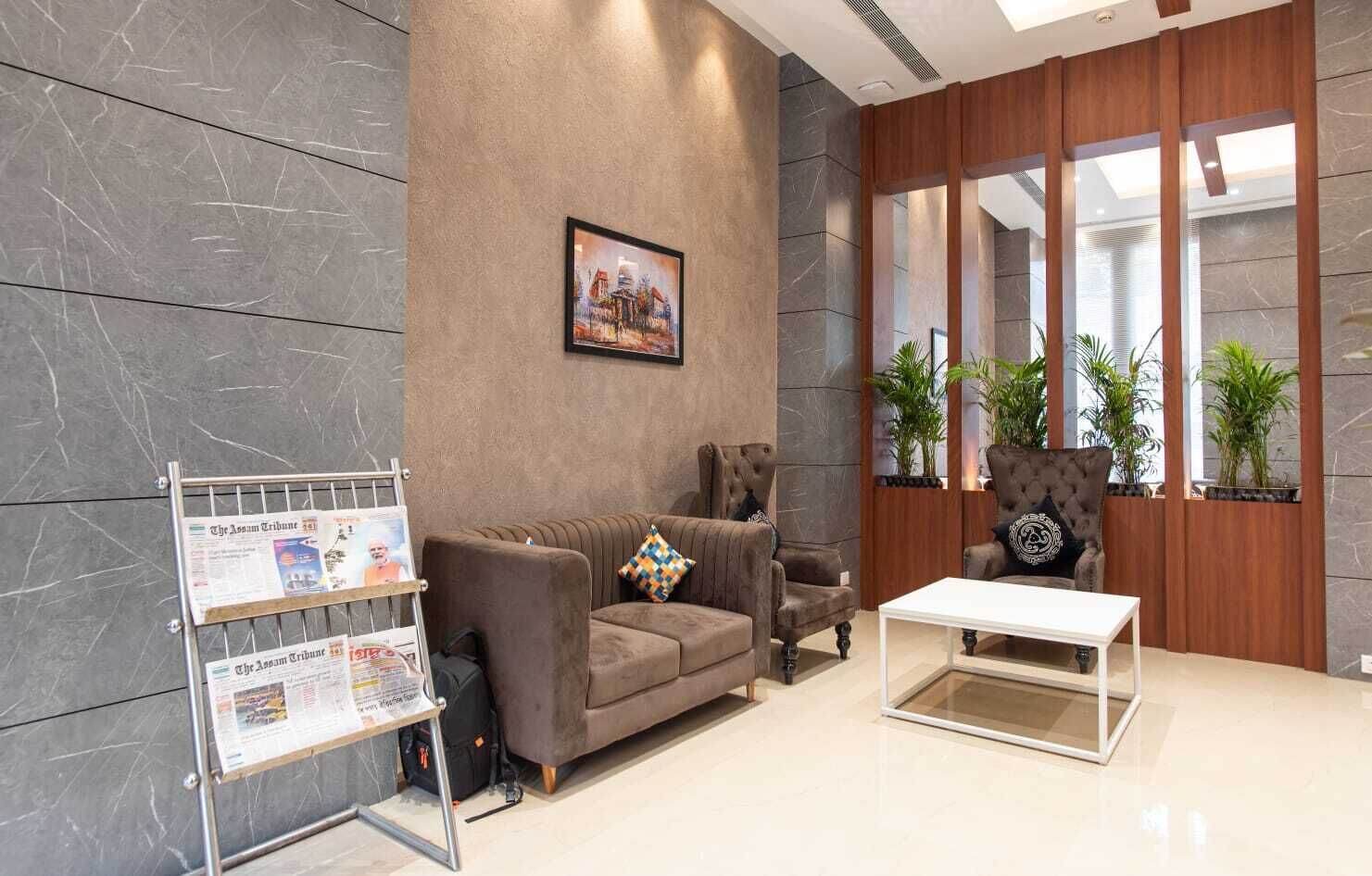 Un vestíbulo moderno con un sofá, sillones, una mesa de centro y un atril para periódicos en la pared.