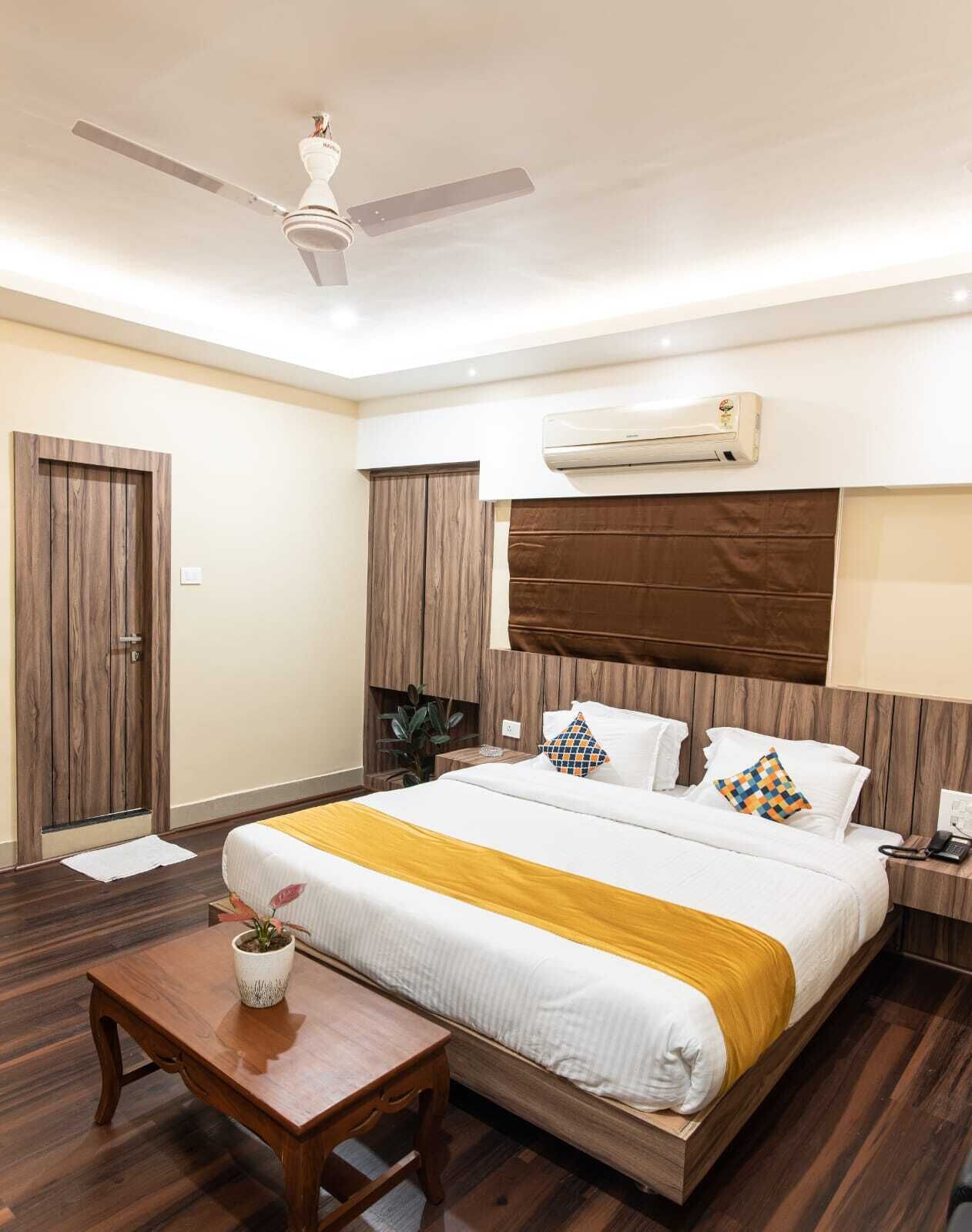Une chambre d’hôtel avec un lit, une table de chevet et un ventilateur de plafond.