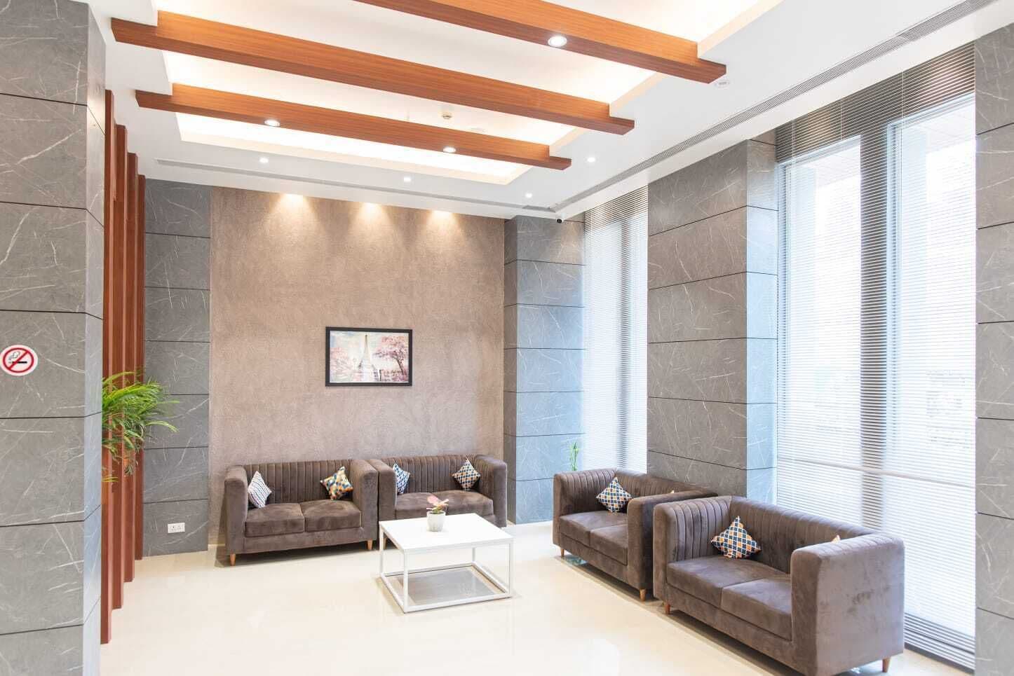A modern lobby with a seating area, a framed picture on the wall, and a large window with blinds.