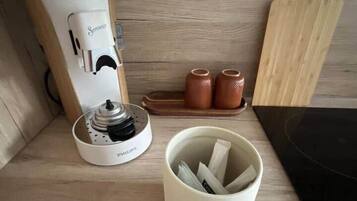 Ein Holztisch mit einer weißen Philips-Kaffeemaschine, einer Keramiktasse und einem Holzschneidebrett.