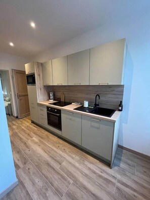 Una cocina moderna con armarios de colores claros, un lavamanos negro y una encimera de madera.