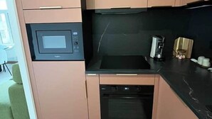 Une cuisine compacte équipée d’un four à micro-ondes, d’un four traditionnel et d’une machine à café.