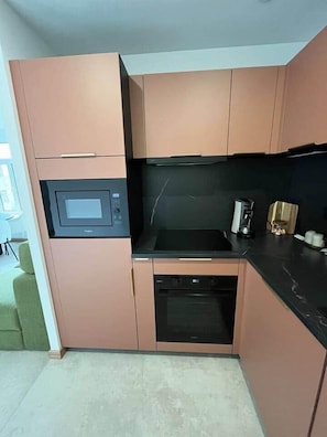 A compact kitchen with a microwave, oven, and a coffee maker. - Bayt al Nour | Designer & Cozy Apartment (Givet)