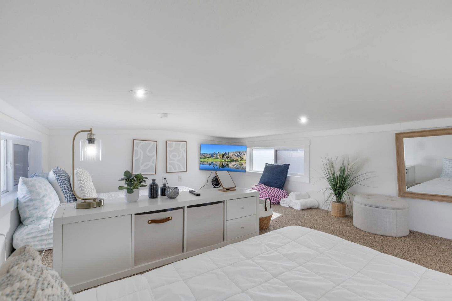 A modern bedroom with a large bed, a bedside table, a TV, and a window.