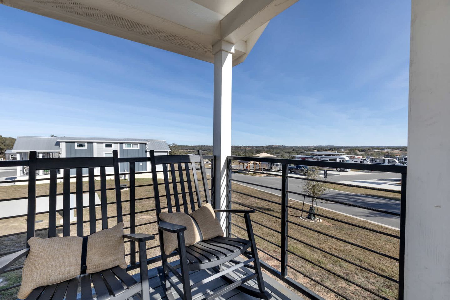 A balcony with a view of a parking lot and buildings.