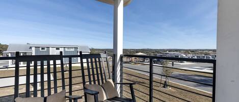 A balcony with a view of a parking lot and buildings.