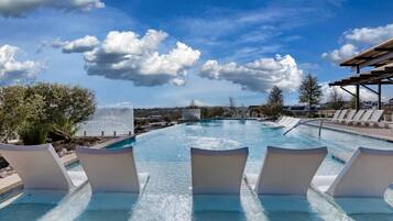 A swimming pool with lounge chairs and a view of the ocean.