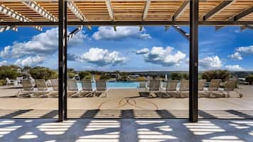 A covered outdoor area with lounge chairs and a pool.