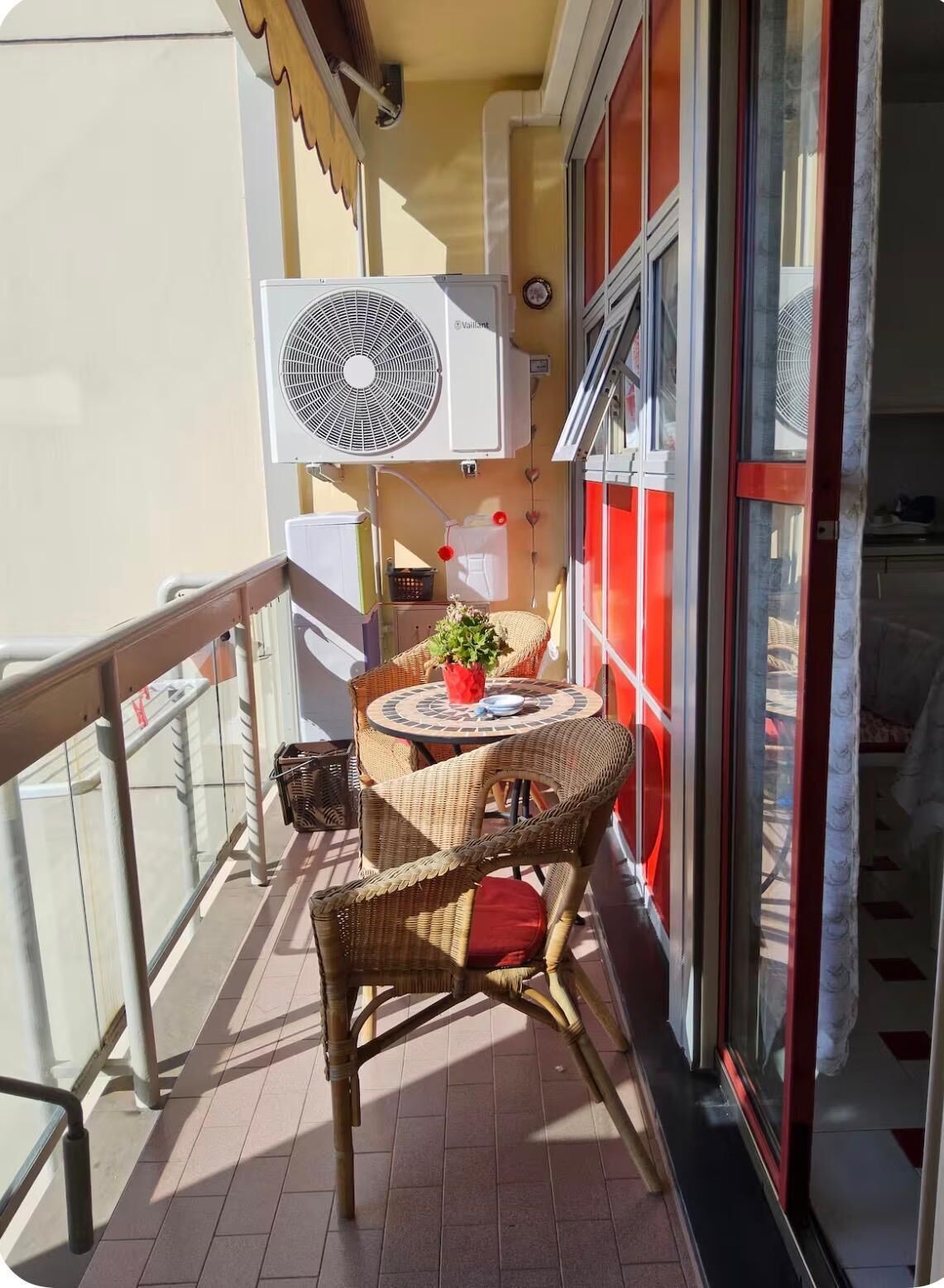 A balcony with a table and chairs, a fan, and a potted plant.
