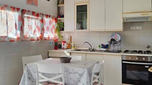 Una cocina moderna con armarios blancos, una estufa a gas y un comedor con mesa y sillas.