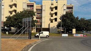 Un edificio de varios pisos con un letrero de 'prohibido el acceso', una furgoneta estacionada al frente y un cartel anunciando 'PISCINE RIVIERA'.