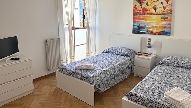 Un dormitorio con dos camas, un televisor, un radiador y un cuadro de globos aerostáticos.