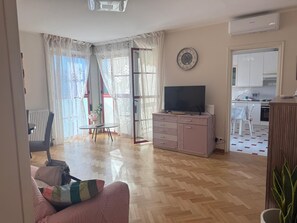 Ein Wohnzimmer mit Fernseher, Essbereich und Küche.