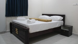 A single bed with white linens, a wooden headboard, and a nightstand. - Swamy Ramana Residency (Tiruvannamalai)
