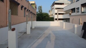 A courtyard with buildings on either side, featuring balconies and a clear sky. - Swamy Ramana Residency (Tiruvannamalai)