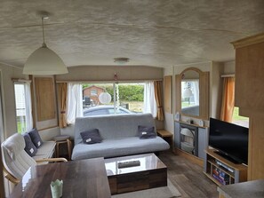 Ein kompaktes Wohnmobil-Interieur mit einer Sitzecke, einem Couchtisch, einem Fernseher und einer kleinen Küchenzeile.