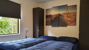 Ein Schlafzimmer mit Bett, Fenster und Wandbild.
