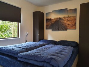 Ein Schlafzimmer mit Bett, Fenster und Wandbild.