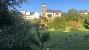 Ein Gebäude mit einem Turm, umgeben von viel Grün und einer Rasenfläche.