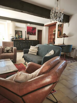 Un salon comprenant un fauteuil en cuir, un canapé, un meuble et un lustre.