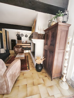 A living room with a sofa, a dining table, a cabinet, and a potted plant.