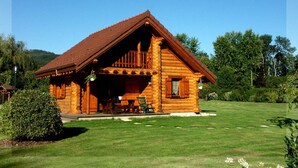 A log cabin with a porch, a dining table, and a chair outside.