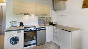 A compact kitchen with a washing machine, a dishwasher, a stove, and a sink. - Apartment 'La Clésinerie' with Private Pool, Private Terrace and Wi-Fi (Badefols-sur-Dordogne)