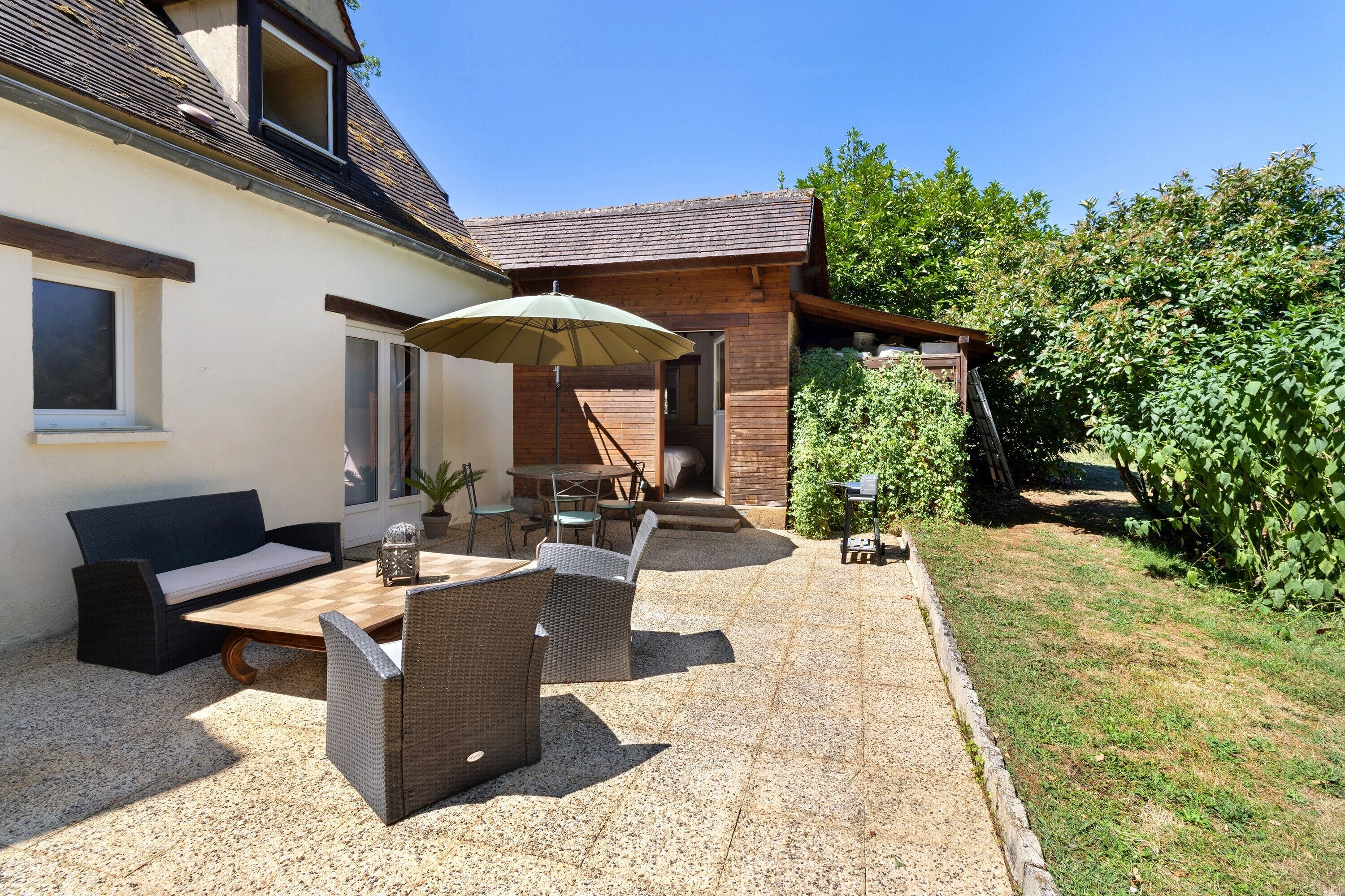 Eine Terrasse mit Gartenmöbeln, einem Tisch und einem Stuhl.