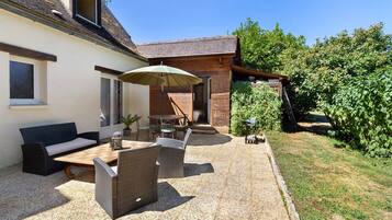 Eine Terrasse mit Gartenmöbeln, einem Tisch und einem Stuhl.