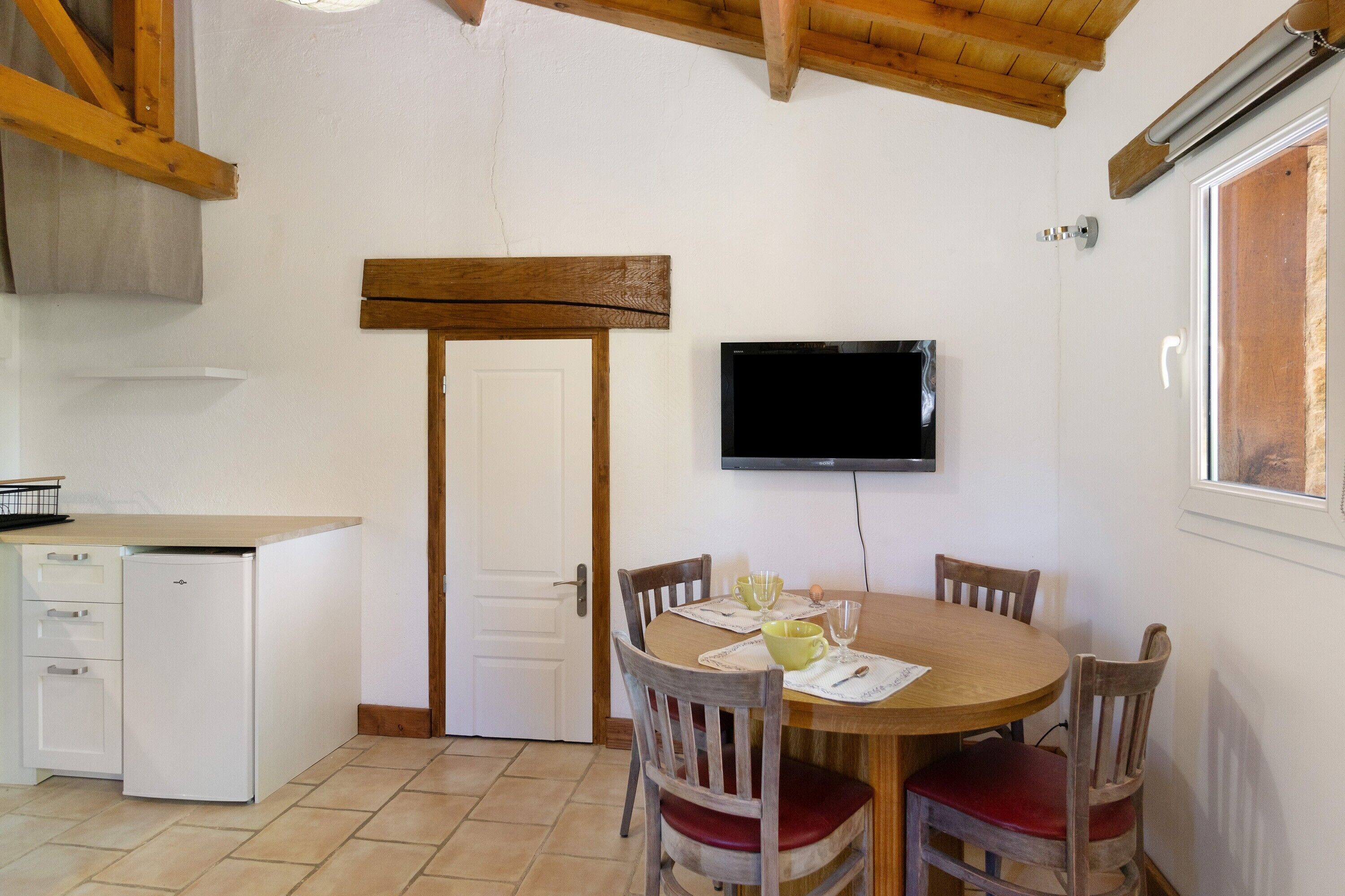 A compact kitchen with a white refrigerator, a wooden door, and a dining area with a round table and four chairs.
