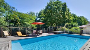 A rectangular swimming pool with a wooden deck, surrounded by a fence and trees. - Apartment 'La Clésinerie' with Private Pool, Private Terrace and Wi-Fi (Badefols-sur-Dordogne)
